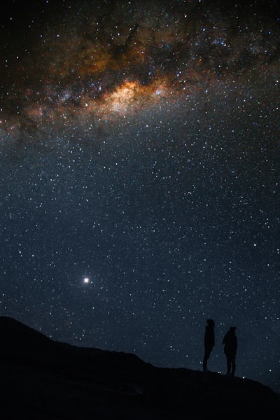 夜晚银河系天空下站着的两个人的剪影